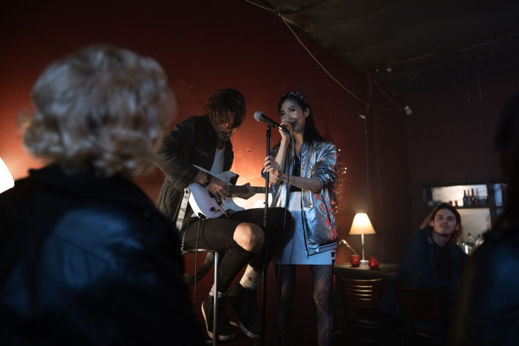 Woman singing karaoke in a small bar while friends cheer